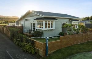 a small white house with a wooden fence at Character Villa Oasis - Pool & Beach in Athenree