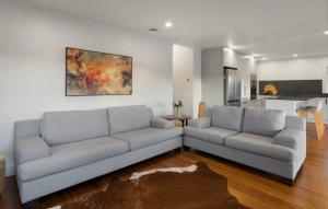 a living room with two couches and a kitchen at Character Villa Oasis - Pool & Beach in Athenree
