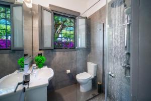 a bathroom with a sink and a toilet and windows at Barbati Beachfront - Pool Villa in Barbati +22 photos