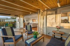 a porch with chairs and a table and a living room at Character Villa Oasis - Pool & Beach in Athenree