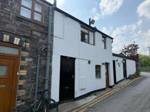 a white house with a bike parked in front of it at Triangle Inn Coachouse in Rhayader