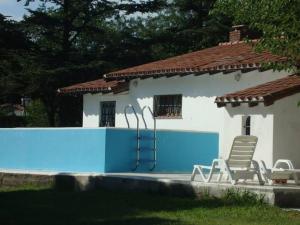 a house with a blue wall and two lawn chairs at Pinos del Virrey I in Valle Hermoso