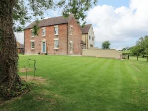 an old brick building with a large grass yard at Highfields Farm in Church Stretton