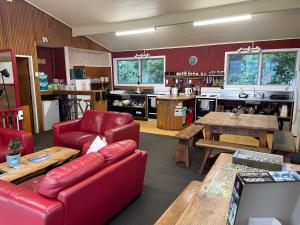 a living room with a red couch and tables at Punakaiki Beach Hostel in Punakaiki