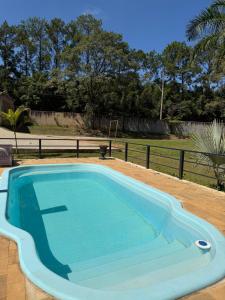 a large blue swimming pool in a yard at Vila do Tênis in Guaratinguetá