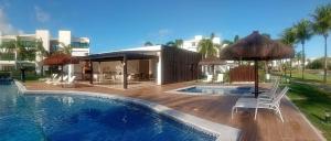 a pool with chairs and umbrellas next to a building at Cond Mediterrâneo I - Iberostate in Praia do Forte