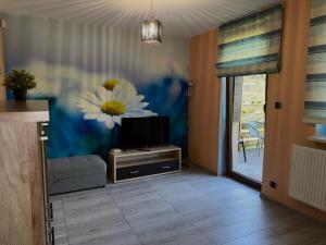 a living room with a tv and a flower on the wall at Agroturystyka Ostoja Wilków I in Wilków