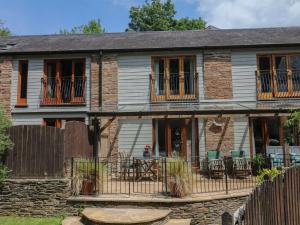 an old stone house with a fence and a patio at Fixit Cottage in Kingsbridge