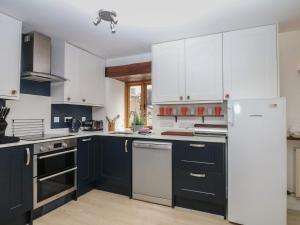 a kitchen with white cabinets and black appliances at Fixit Cottage in Kingsbridge