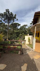 a wooden bench in front of a house with flowers at Green Valley Hydro Suite - Monte Verde-MG in Camanducaia