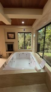 a large bath tub in a room with windows at Green Valley Hydro Suite - Monte Verde-MG in Camanducaia +29 photos