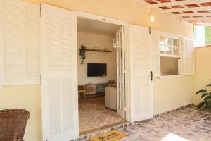 a room with white shuttered doors and a television at Casa Laguna - Geribá in Búzios