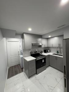 a kitchen with white cabinets and black appliances at The Basement apartment in Milton