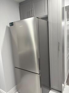 a stainless steel refrigerator in a kitchen with white cabinets at The Basement apartment in Milton