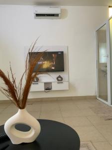 a white vase with a plant in a living room at Residence Emilienne in Cotonou +8 photos