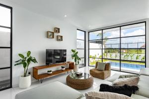 a living room with a couch and a tv and windows at Villa Alba by Orivista, Rice Field View in Dalung