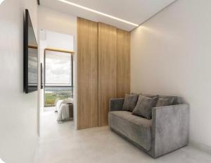a living room with a gray couch and a window at Apartamento no Beach Resort Salinas in Ilha de Atalaia