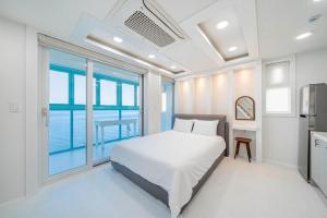 a bedroom with a white bed and a large window at Samcheok Pureun Bada Pension in Samcheok