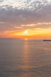 a sunset over the ocean with a ship in the distance at Samcheok Pureun Bada Pension in Samcheok