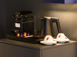 a kitchen counter with a coffee maker and plates on it at Mercure Bucharest Cantemir in Bucharest +182 photos