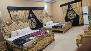 two beds in a hotel room with golditures at Hotel Destination in Sukkur