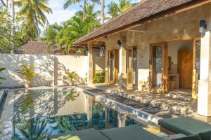 a villa with a swimming pool in front of a house at Kelapa Villas in Gili Trawangan