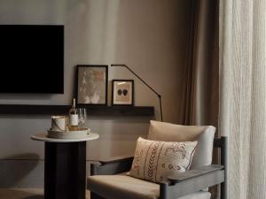 a room with a chair and a table with a lamp at Nirema Hotel & Spa Samos - MGallery Collection in Samos