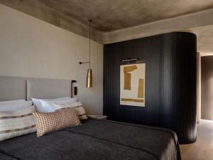 a bedroom with a bed with a black wall at Nirema Hotel & Spa Samos - MGallery Collection in Samos