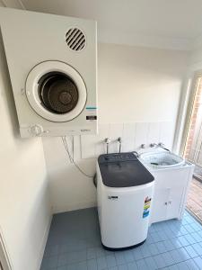 a bathroom with a toilet with a washing machine at Baybreeze - Bring your own linen in South West Rocks