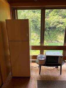 a refrigerator and a microwave in a room with a window at YAMAYA BASE 1 in Ōkawamochi