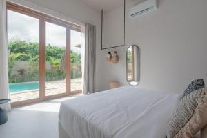 a white bedroom with a bed and a large window at Tayo Villa in Ahangama