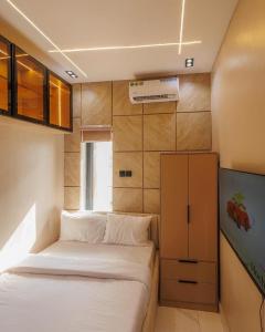 a small bedroom with a bed and a cabinet at Tiny Studio Apartment with Pool and gym in Lekki +3 photos