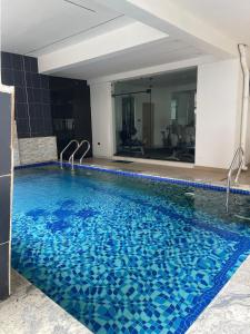 a large swimming pool with blue water in a building at Tiny Studio Apartment with Pool and gym in Lekki