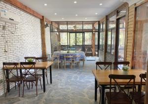 a room with tables and chairs and a brick wall at 莫干山后舍民宿 in Deqing