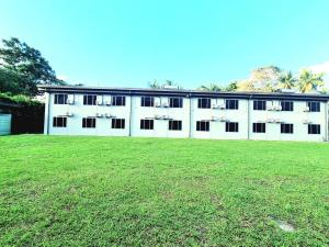 a white building with windows and a grass field at Red Palm Hotel in Suva