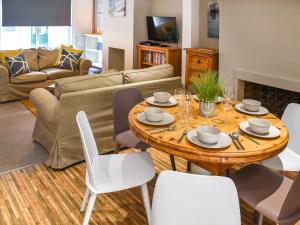 a living room with a wooden table and white chairs at Waverley Cottage in Mundesley