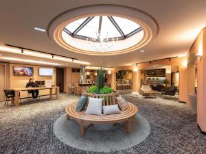 an office lobby with a large skylight and a table at Novotel Macon Nord - Porte de Bourgogne in Mâcon