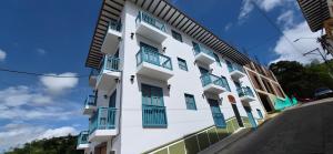 a white building with blue balconies on it at Portón del Río Jericó in Jericó