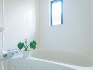 a white bathroom with a tub and a potted plant at Green Peak 1 in Aso