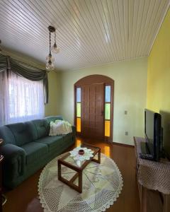 a living room with a green couch and a table at Casa Bella Vita in Pinto Bandeira
