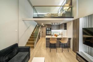 a living room and kitchen with a staircase and a couch at Aster Apartments - Stylish Loft with Rooftop Pool & Sauna in Canggu