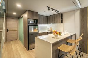 a kitchen with a island with two chairs and a counter at Aster Apartments - Stylish Loft with Rooftop Pool & Sauna in Canggu