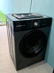 a black washing machine sitting in a room at Dino House in Taiping