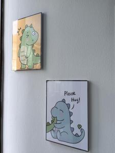two signs hanging on a wall with a dinosaur at Dino House in Taiping