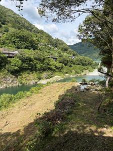 a river in the middle of a hill with trees at YAMAYA BASE 1 in Ōkawamochi