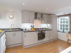 a kitchen with white cabinets and stainless steel appliances at Dayan Cottage in Fowey