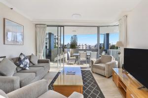 a living room with a couch and a tv at Pumicestone Blue in Caloundra