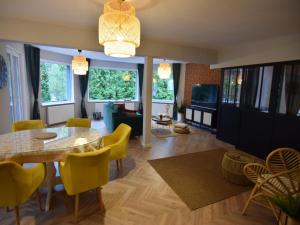a living room with a dining table and yellow chairs at Comfortable Jacuzzi Apartment for 8 in Stezyca in Stężyca
