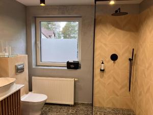a bathroom with a shower and a toilet and a window at Comfortable Jacuzzi Apartment for 8 in Stezyca in Stężyca +22 photos