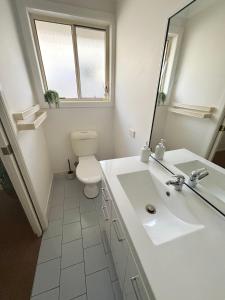 a bathroom with a sink and a toilet and a mirror at Baybreeze - Bring your own linen in South West Rocks +11 photos